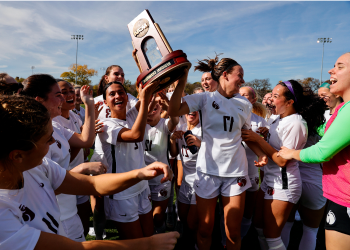 Makena Rietz (17) and Madison Ibale (2) celebrate with teammates by hoisting the NCAA Division II West Region women’s soccer championship trophy.